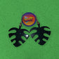 A pair of custom black monster leaf earrings on a Green Leaf Earrings by Kustom Jewelry background.